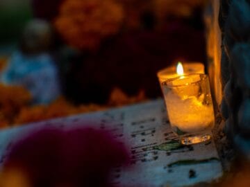 A lit candle beside a framed pet photo as a memorial keepsake